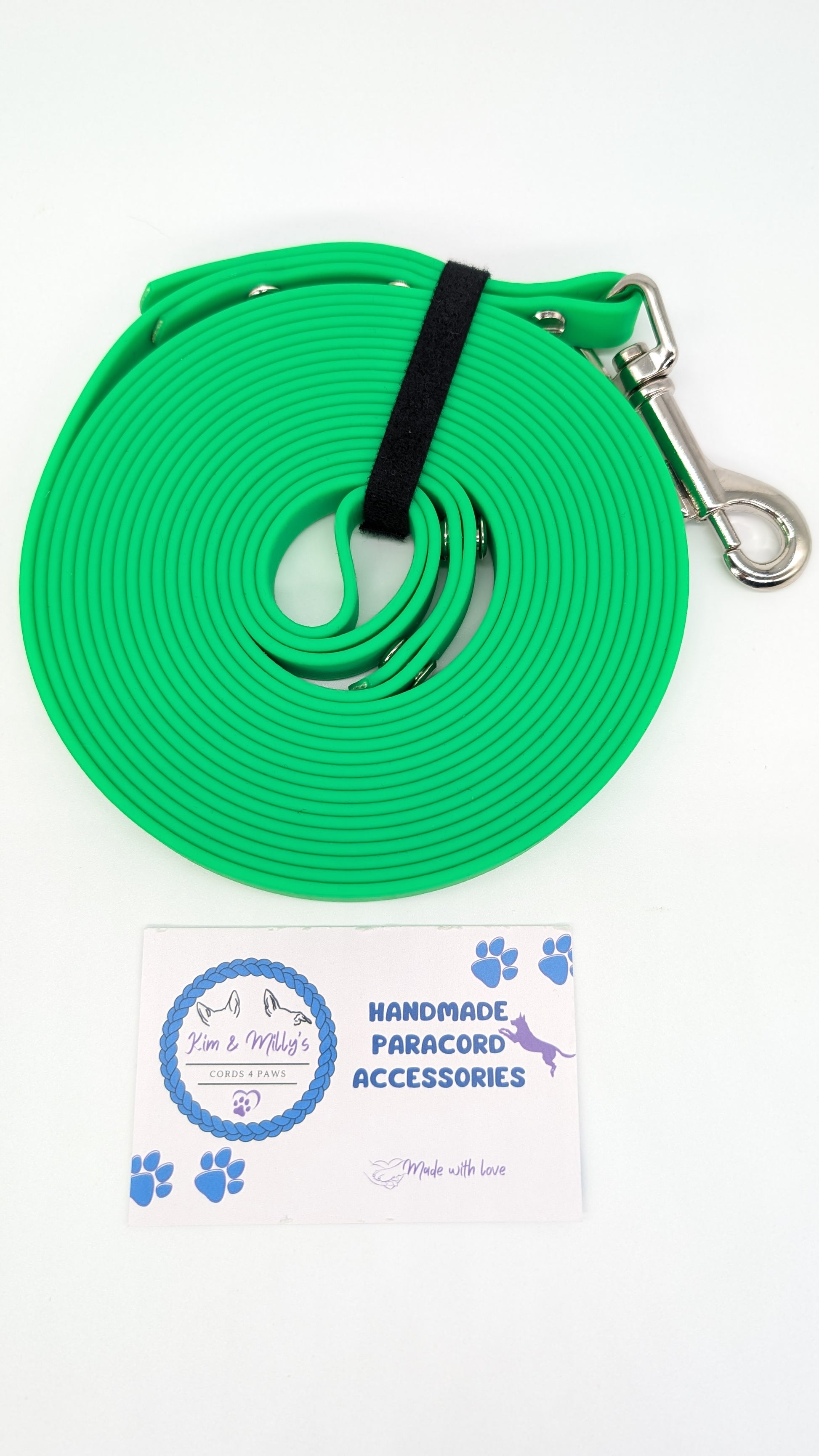 Green paracord leash with metal clip on a white background, featuring a brand label.