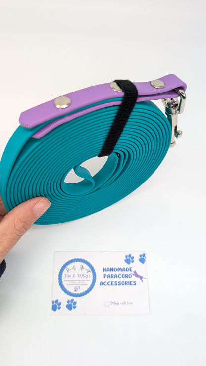 Pet leash with purple handle held by a hand on a white background