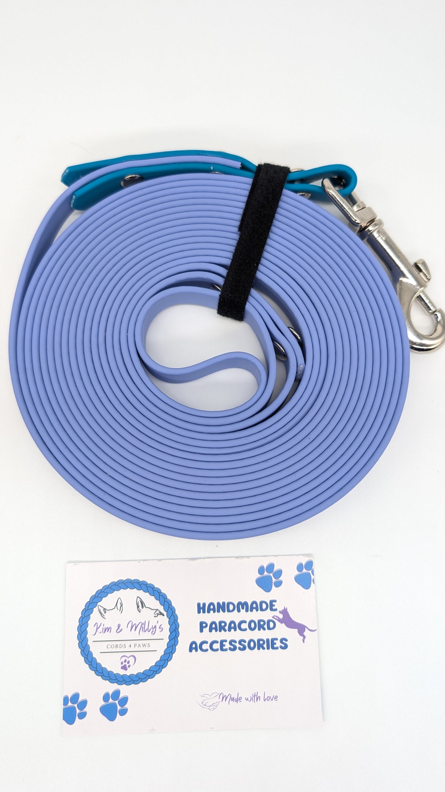 Blue paracord leash with metal clip on a white background, featuring a brand label.