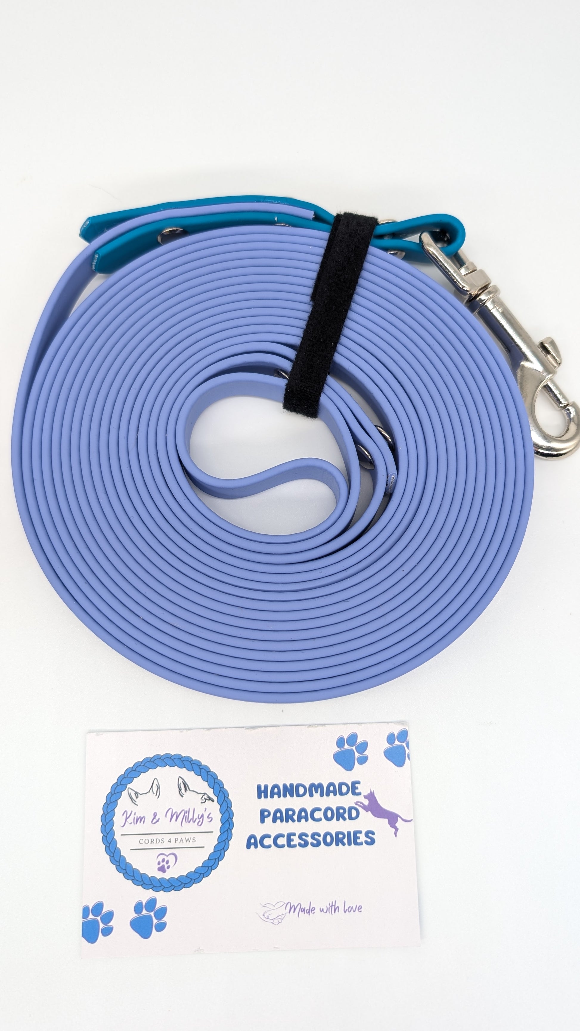 Blue paracord leash with metal clip on a white background, featuring a brand label.